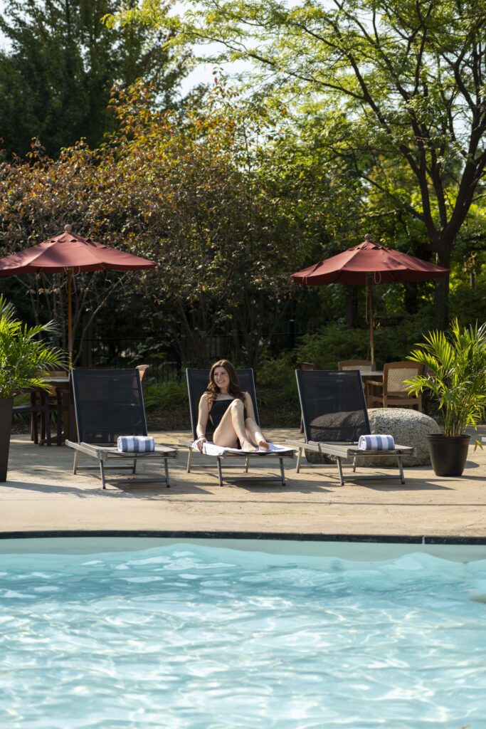 Woman enjoying a sunny afternoon by the outdoor pool at Georgian Bay Hotel near Blue Mountain.