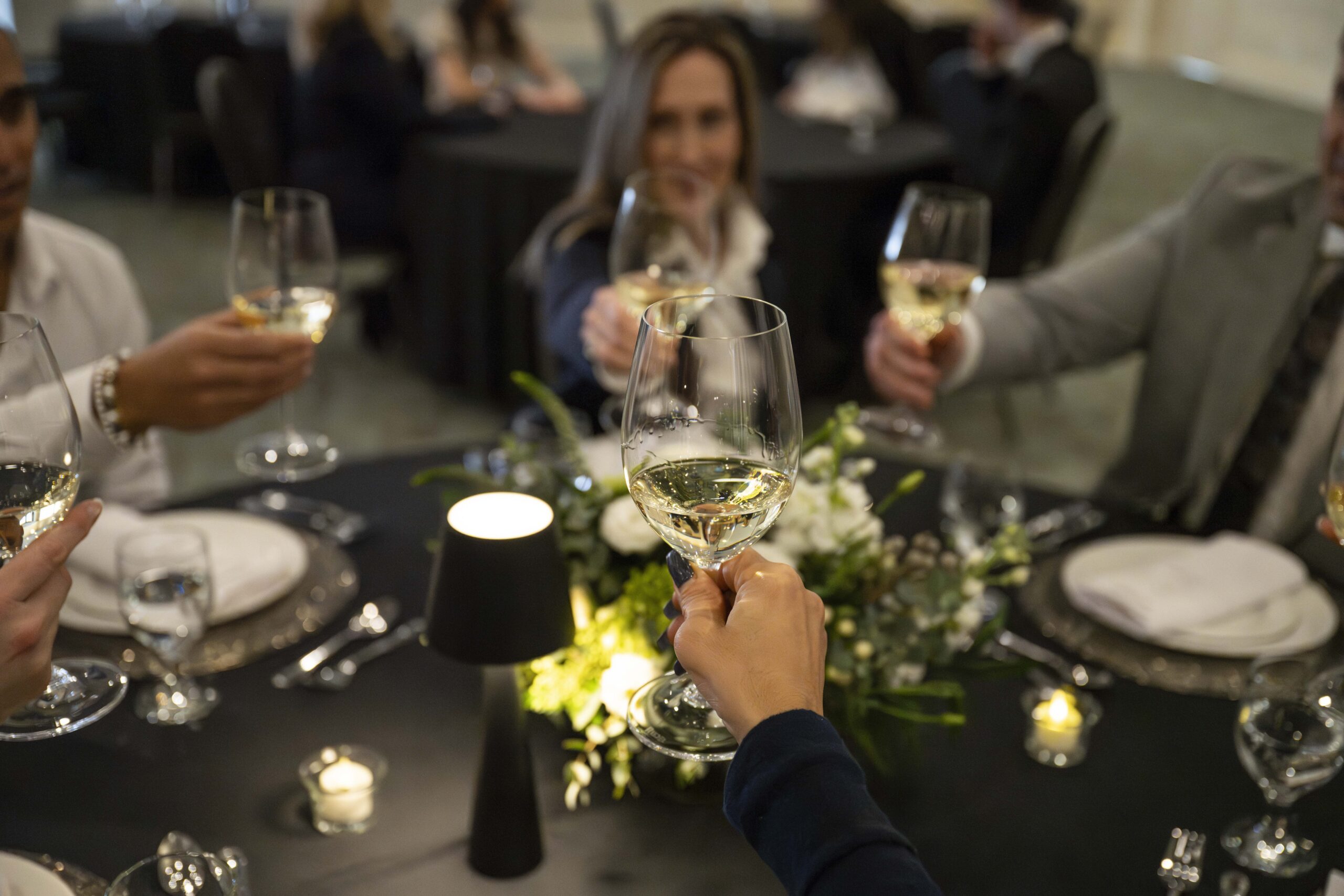 Guests raising their glasses in a festive toast around an elegantly decorated holiday party table in the ballroom at Georgian Bay Hotel in Collingwood.